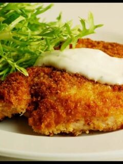 Easy homemade fried chicken served with sour cream on a white plate.