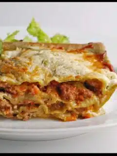 A slice of lasagna with a salad on a white plate featuring Lasagne Verdi al Forno from Emilia-Romagna.