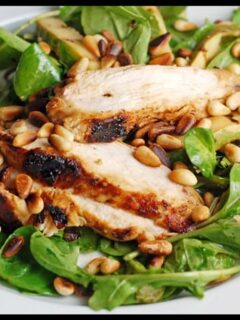 Grilled chicken salad with spinach and pine nuts, featuring zucchini.