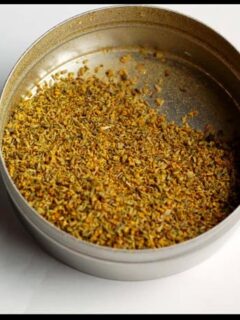 A tin of dried herbs in a metal container, such as Red Peppers or Fennel Pollen.