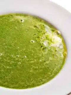A bowl of fresh spring pea soup on a white table.