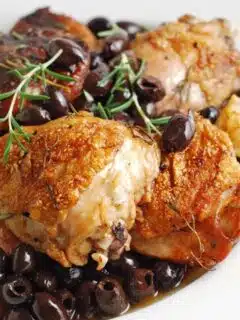 Served in a white bowl, this dish features chicken and black olives.