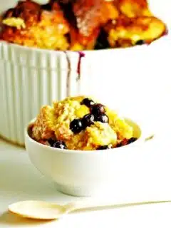 Indulge in a bowl of delectable blueberry bread pudding topped with a spoon.