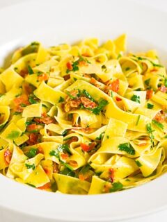 A white bowl of creamy pasta with parsley.