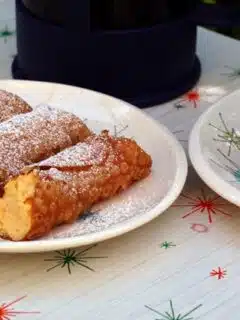 A plate of pumpkin cannoli and a cup of coffee on a table.