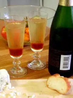 A bottle of champagne sits beside a slice of bread on a cutting board.