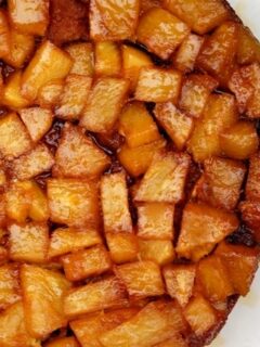A white dish topped with sliced apples and pineapple.
