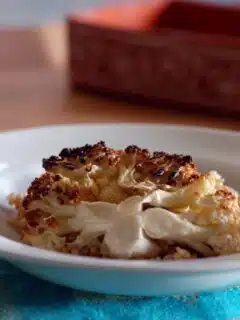 A bowl of roasted cauliflower on a table, paired with Baharat scented rice.