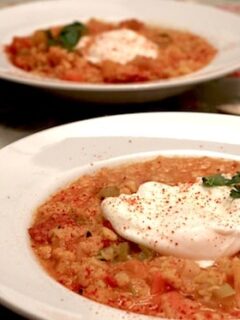 Two bowls of yellow lentil soup with a poached egg on top, garnished with chorizo.