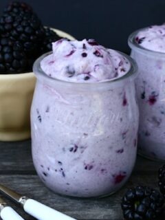 Two jars of yogurt with blackberries and spoons resemble Blackberry Cheesecake Pots.