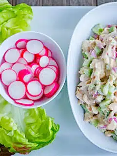 A plate with lettuce salad and radishes on it.