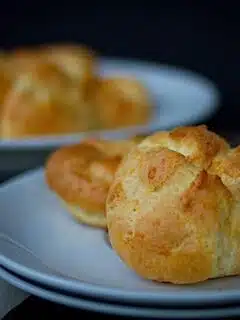 A plate of gougeres on a wooden table.