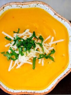 A bowl of homemade sweet potato soup garnished with cheese and parsley.