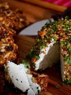 A Blue Cheese Ball with nuts on the cutting board.