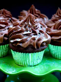 Grasshopper cupcakes with chocolate frosting on a green plate.
