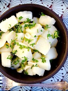 A bowl of potato salad with fresh parsley.