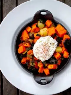 Roasted sweet potatoes with a poached egg on a plate, creating a tasty dish perfect for breakfast or brunch.