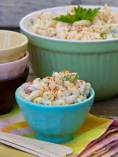 Classic Macaroni Salad in colorful bowls on a wooden table.