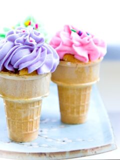 Three birthday cupcakes in a cone on a plate.