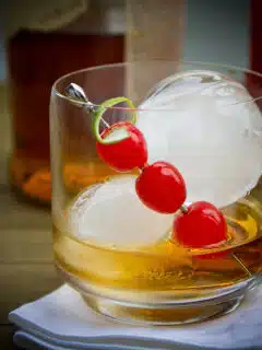 A Ole Smokey Cocktail garnished with cherries and ice in a glass.