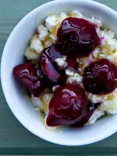A white bowl filled with cherries, homemade ricotta.
