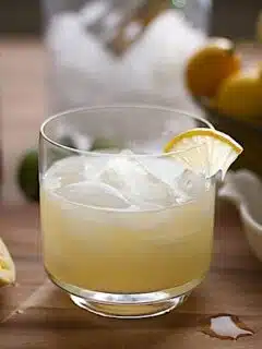 A glass of Preserved Meyer Lemon Cocktail on a cutting board.