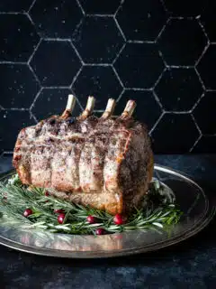 A pork prime rib roast with rosemary and cranberries on a plate.